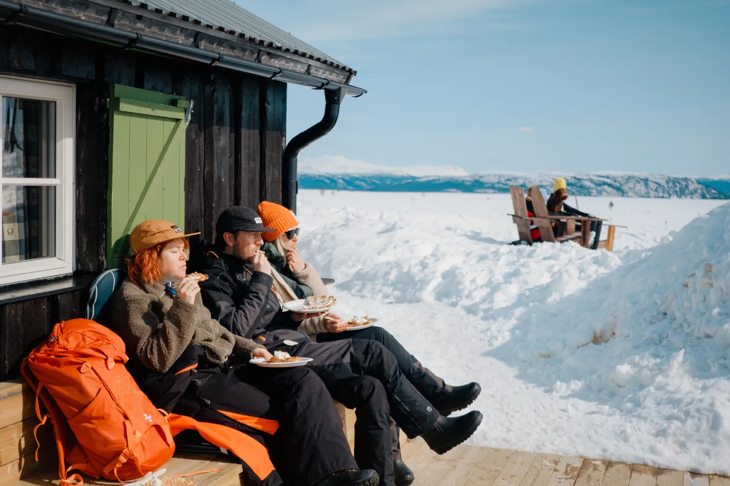 En grupp människor som sitter på en veranda och äter mat utanför