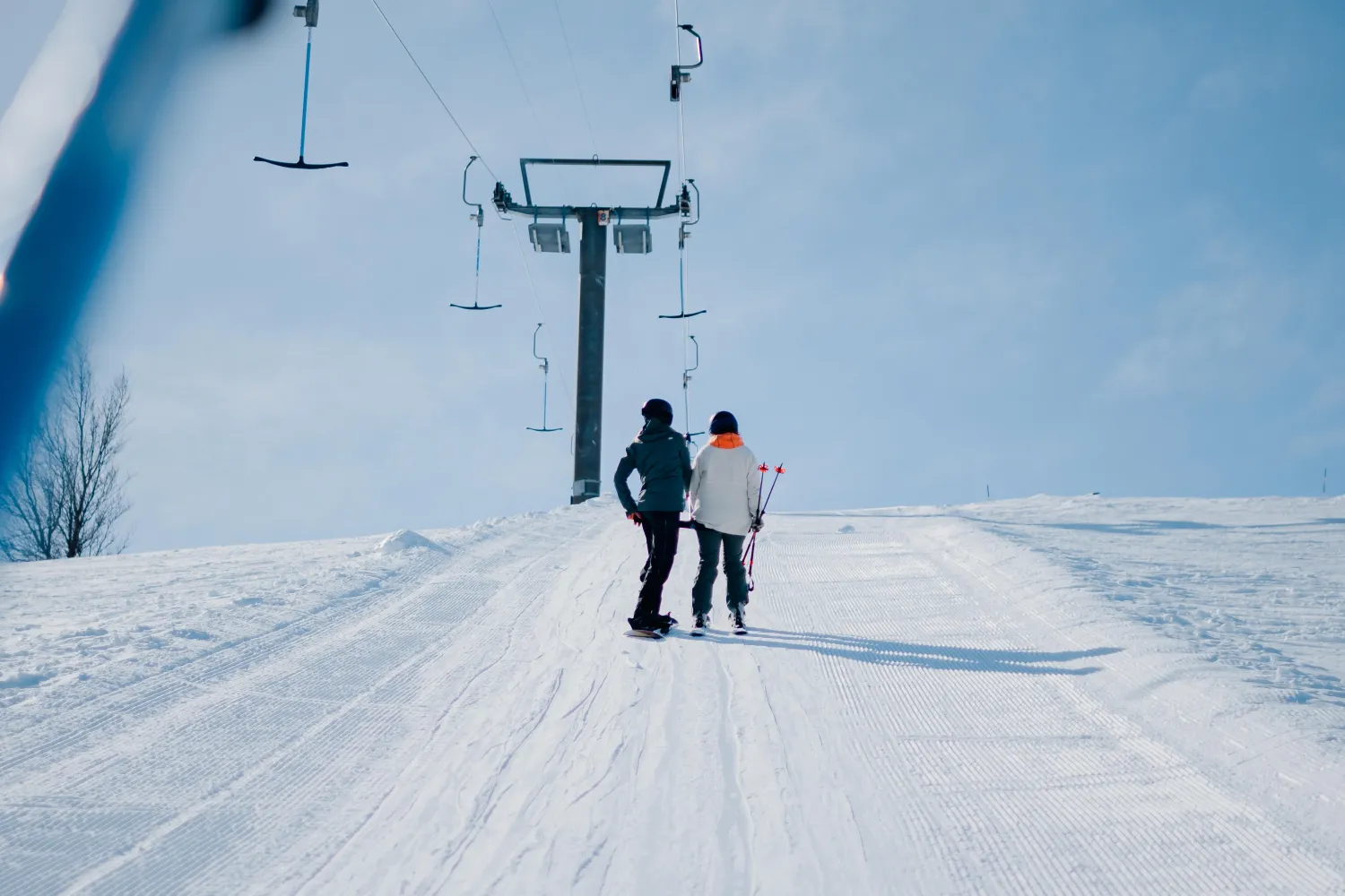 Två personer som åker skidor på en snöig kulle